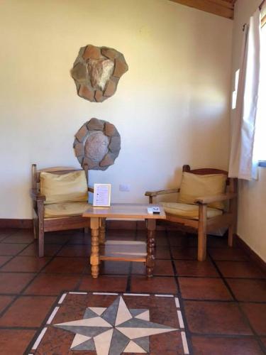 a room with two benches and a table and a wall at El Viento De Mi Sueño in Tafí del Valle