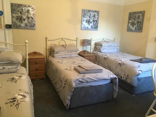 a bedroom with two beds and a dresser at Oak Tree Guest House in Farnborough