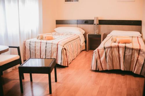 a hotel room with two beds and a table at B&B Santa Monica in Pero