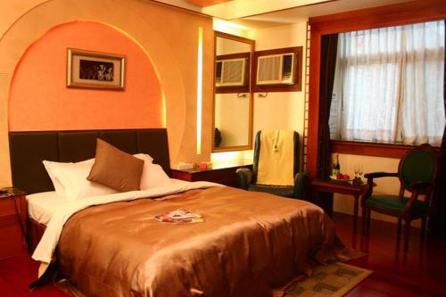 a bedroom with a bed and two chairs and a window at Yatelanda Motel in Shalu