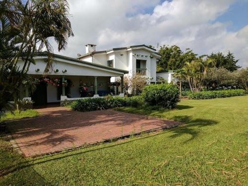 a large white house with a grass yard at Casa Finca Paititi in San Antonio de Pereira