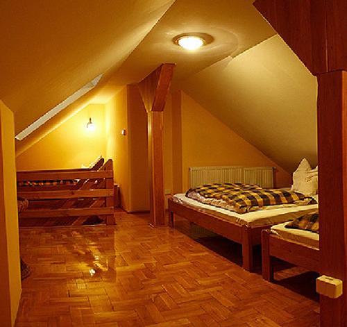 a attic room with two beds and a wooden floor at Villa Senator with access Kitchen - Adults Only in Zielona Góra