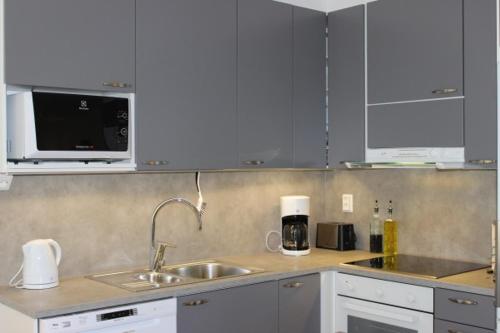 a kitchen with white cabinets and a sink and a microwave at Majoituspalvelu Nurmi Apartment Yritysperänkatu 2 E 2 (Centre of Raahe) in Raahe