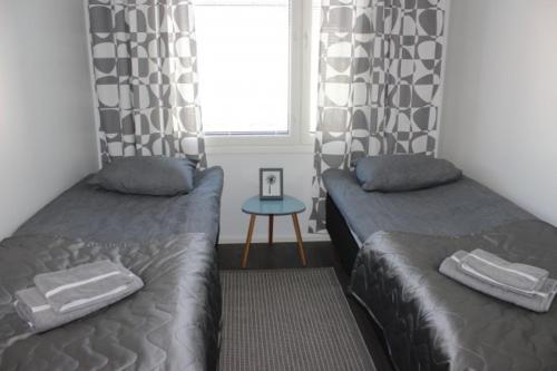 a bedroom with two beds and a window and a table at Majoituspalvelu Nurmi Apartment Yritysperänkatu 2 E 2 (Centre of Raahe) in Raahe