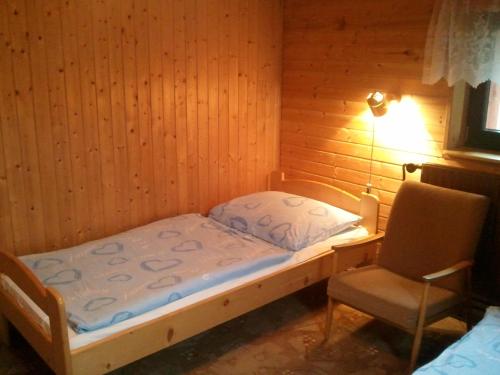 a small bedroom with a bed and a chair at Chata Bajama in Bedřichov