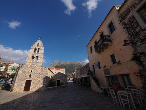 a stone building with a tower in a street at Sophia Areopoli Guesthouse in Areopolis
