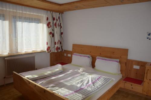 1 dormitorio con 1 cama de madera y 2 almohadas en Neuner Charlotte Preise inclusive Sommercard, en Wenns