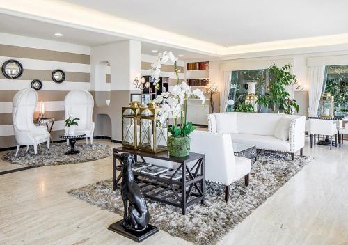 a living room with white furniture and white chairs at Hotel Ascona in Ascona