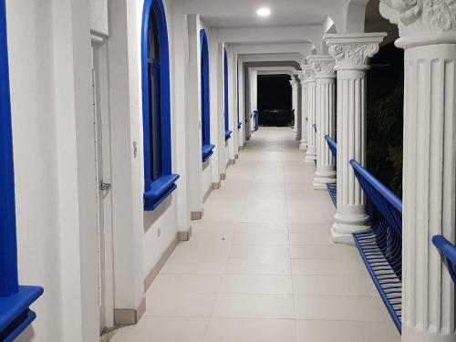 a corridor of a building with blue and white columns at Hotel Las Palmas de OSA in Ciudad Cortés