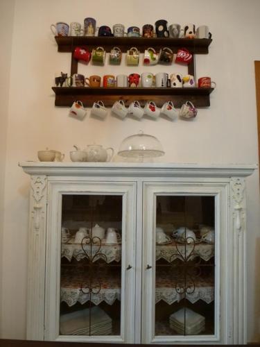 a white cabinet with cups and dishes on a wall at B&B A Casa di Mael in San Costanzo