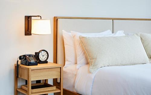 a bed with a clock on a night stand next to it at Shinola Hotel in Detroit