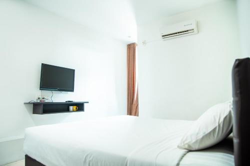 a bedroom with a white bed and a tv at Shuang Ling Inn in Miri