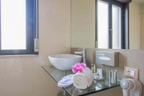 a bathroom with a sink and a glass table with towels at Villa Morgana Resort and Spa in Torre Faro