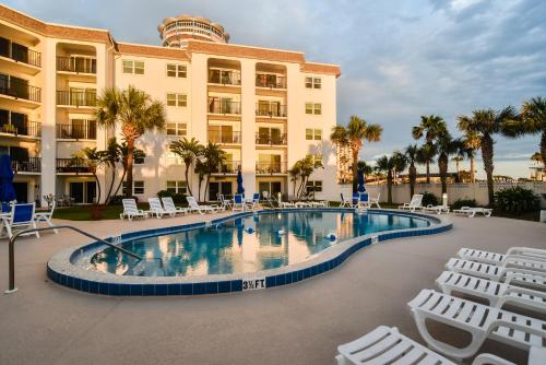 a hotel with a swimming pool and chairs and a building at Daytona Beach Shores Condos in Daytona Beach Shores