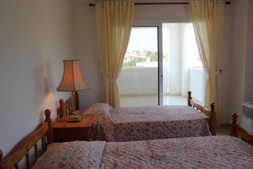 1 dormitorio con 2 camas, lámpara y ventana en Galatia's Court, en Pafos