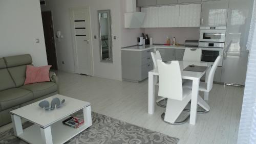 eine Küche und ein Wohnzimmer mit einem Sofa und einem Tisch in der Unterkunft Apartament DeLux in Rewal