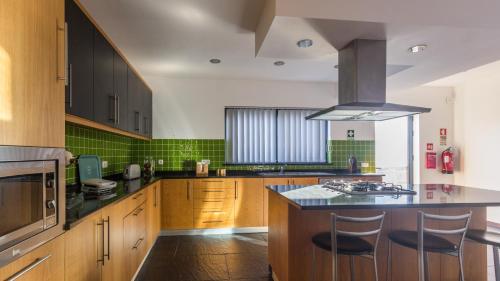 a kitchen with wooden cabinets and a black counter top at Casa Milhafre in Praia da Vitória