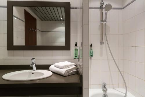 a bathroom with a sink and a shower with a mirror at Hôtel du Béryl, Lons-le-Saunier in Lons-le-Saunier