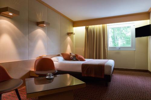 a hotel room with a bed and a window at Hôtel du Béryl, Lons-le-Saunier in Lons-le-Saunier