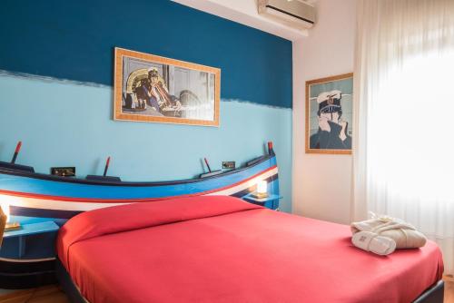 a bedroom with a red bed and blue walls at Villa Morgana Resort and Spa in Torre Faro