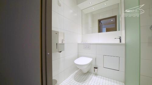 a white bathroom with a toilet and a mirror at Pärnu Rannastaadioni Hostel in Pärnu