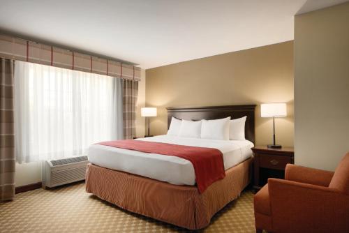 a hotel room with a large bed and a chair at Country Inn & Suites by Radisson, Des Moines West, IA in Clive
