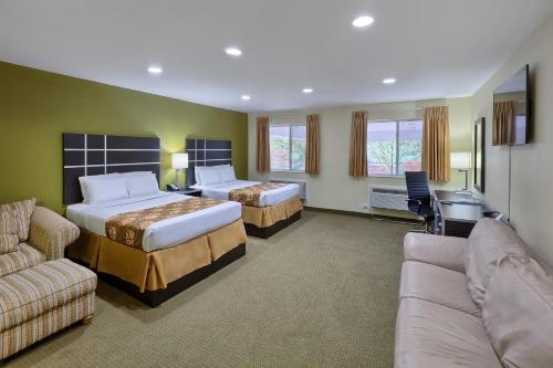 Habitación de hotel con 2 camas y sofá en Country Hearth Inn of Knightdale, en Knightdale