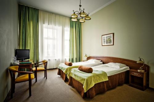 a bedroom with two beds and a desk and a television at Shelfort Hotel in Saint Petersburg