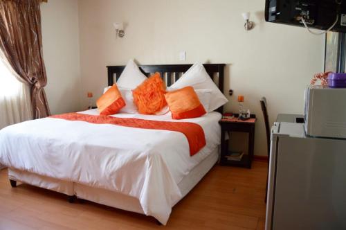 1 dormitorio con 1 cama blanca grande con almohadas de color naranja en Shoes Guest House, en Mthatha