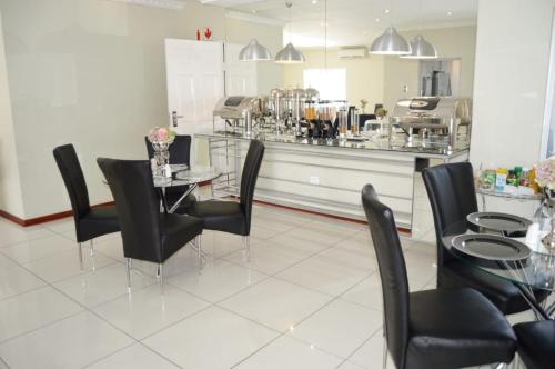 een eetkamer met een glazen tafel en zwarte stoelen bij Shoes Guest House in Mthatha