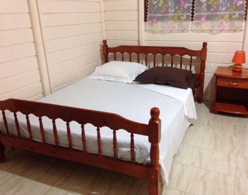 1 dormitorio con cama de madera con sábanas blancas y ventana en Chambre à louer chez l'habitant dans Villa Créole Authentique et en Bois, en Trois-Rivières