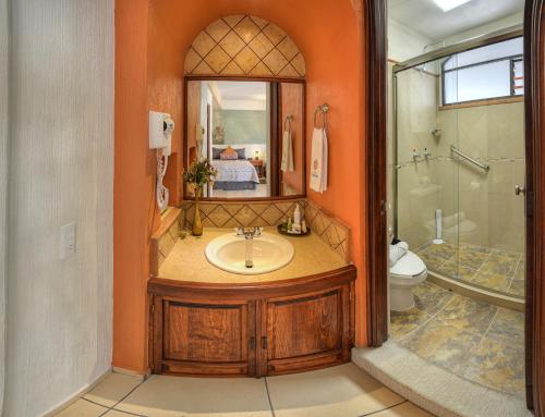 a bathroom with a sink and a toilet and a mirror at Hotel Santa Paula in Taxco de Alarcón
