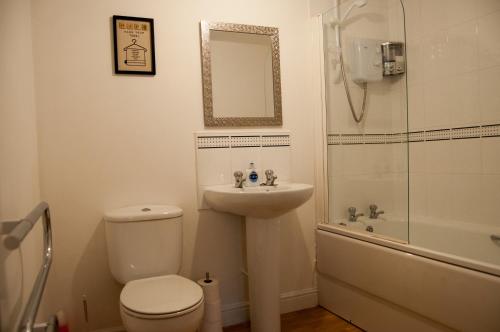 a bathroom with a toilet and a sink and a shower at Bolton Executive Apartment in Bolton