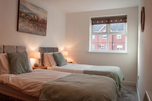 two beds in a room with a window at Bolton Executive Apartment in Bolton