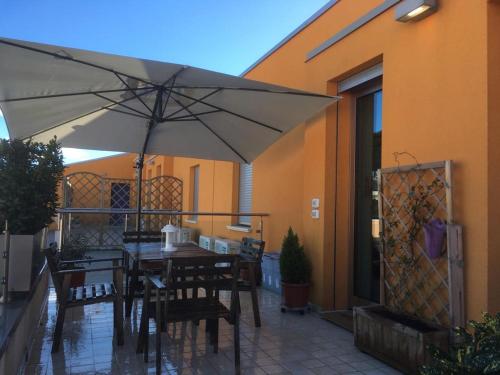 a patio with a table and chairs and an umbrella at L`ATTICO Apartments in Civitanova Marche