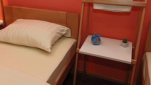 a bedroom with a bed and a nightstand with a clock on it at Apartmani 077 in Drvar