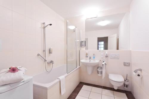 a white bathroom with a toilet and a sink at Aparthotel Neumarkt in Dresden