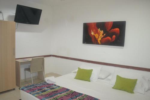 Hotel Calarca Plus في مونتيريا: غرفة نوم بسرير ودهان على الحائط
