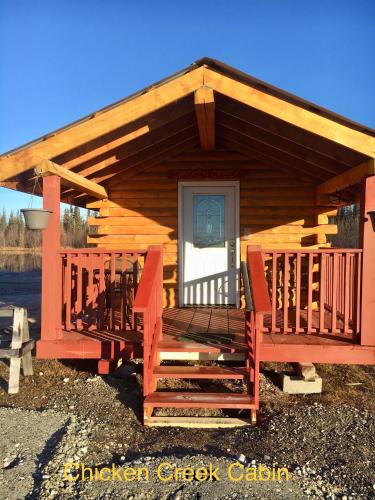 a wooden cabin with a porch and two chairs at Alaska Log Cabins on the Pond in Clear Creek Park