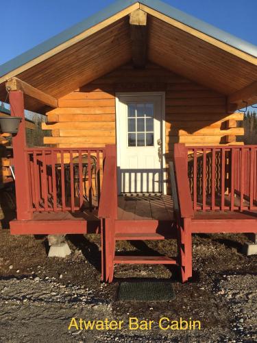 a log cabin with two benches in front of it at Alaska Log Cabins on the Pond in Clear Creek Park