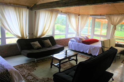 a living room with a couch and a bed and windows at Naturaleza Muisca in Guasca