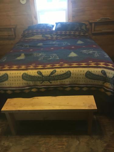 a bed in a room with a table next to it at Alaska Log Cabins on the Pond in Clear Creek Park
