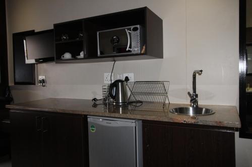 a kitchen counter with a sink and a microwave at Alcazaba Hotel in Johannesburg
