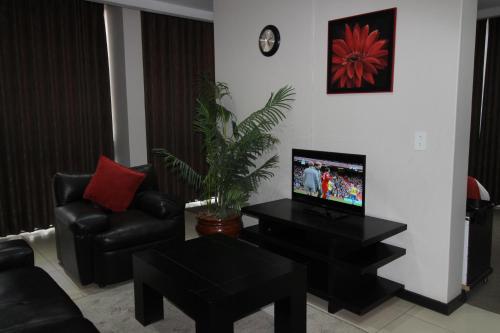 a living room with a couch and a tv and a chair at Alcazaba Hotel in Johannesburg