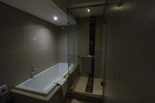a bathroom with a tub and a glass shower at Alcazaba Hotel in Johannesburg
