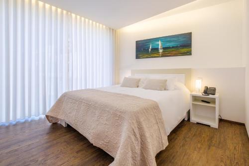 a bedroom with a white bed and a large window at SISU Guest House in Esposende