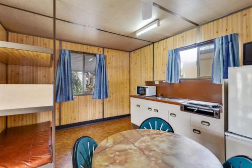 a kitchen with wooden walls and a table with chairs at First City Caravilla in Cairns