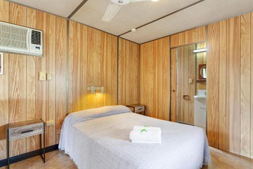 a bedroom with a white bed and wooden walls at First City Caravilla in Cairns