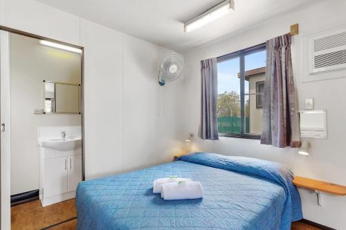 a bedroom with a blue bed and a window at First City Caravilla in Cairns