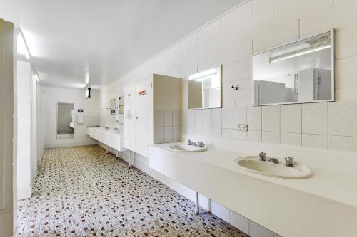 a white bathroom with two sinks and two mirrors at First City Caravilla in Cairns